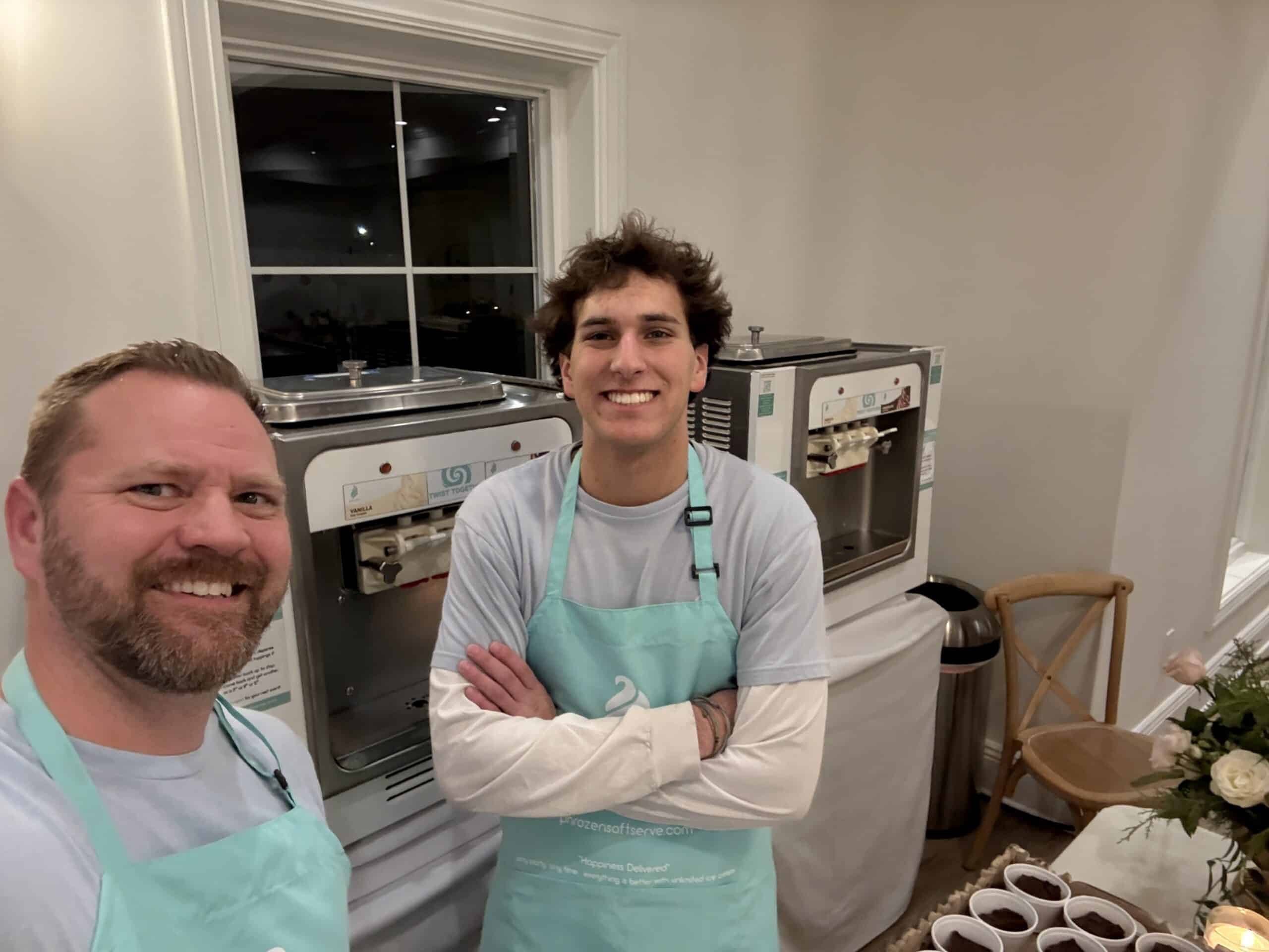 Two Phrozen Soft Serve staff in teal aprons standing beside two soft serve machines at Magnolia in South Jordan