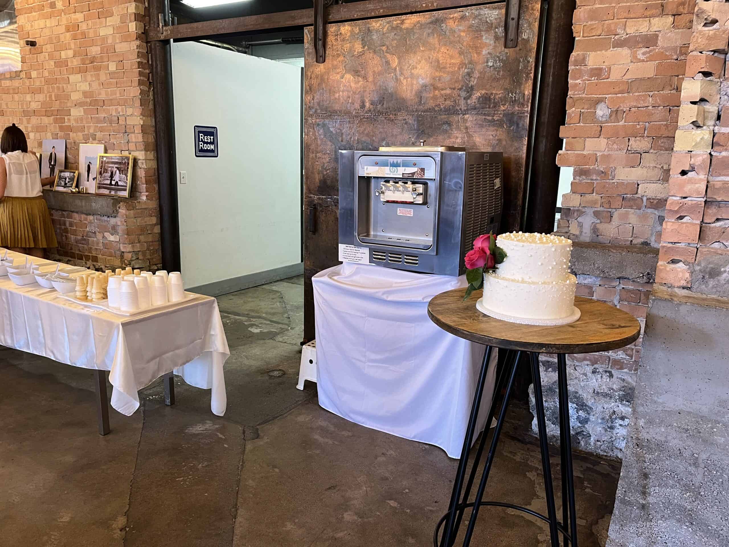 Soft serve machine and a two-tier wedding cake in the brick and steel interior of The Startup Building in Provo
