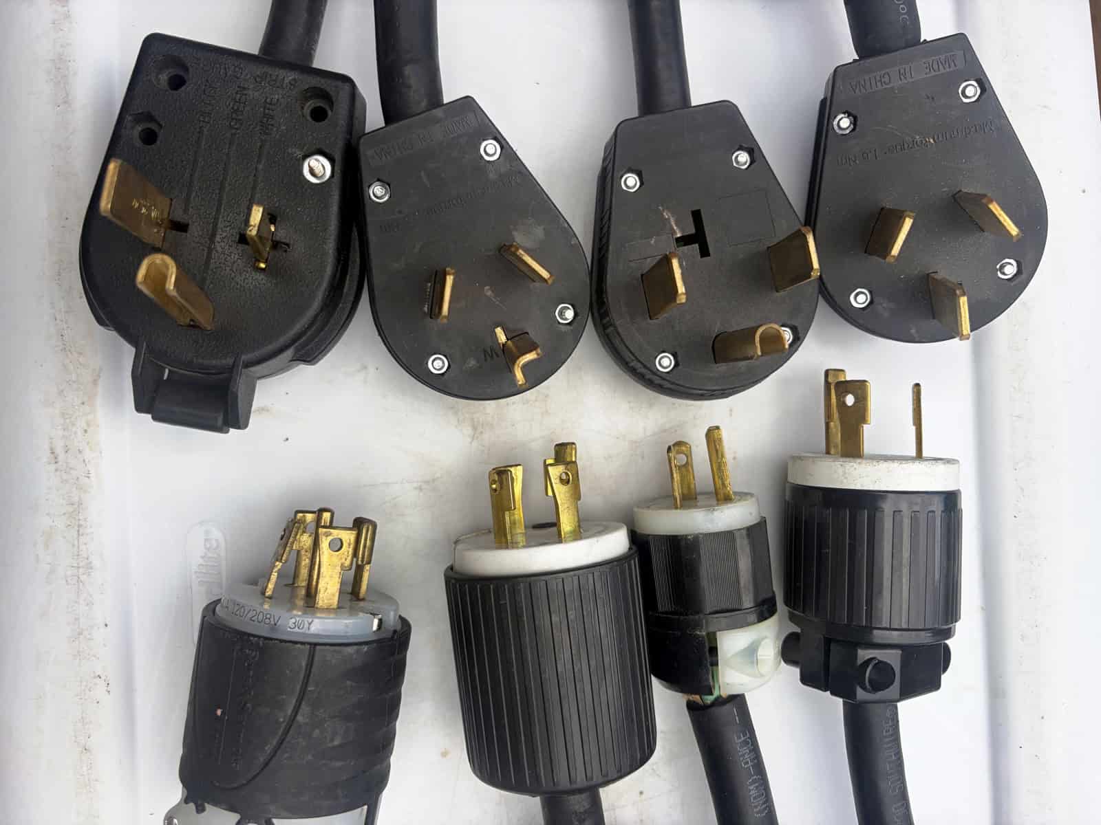 The plug adapters Phrozen Soft Serve carries: four straight-blade dryer and range plugs above, four twist-lock plugs below